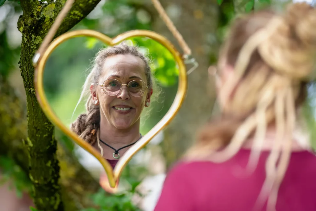 Heike schaut in einen Spiegel mit Herzform